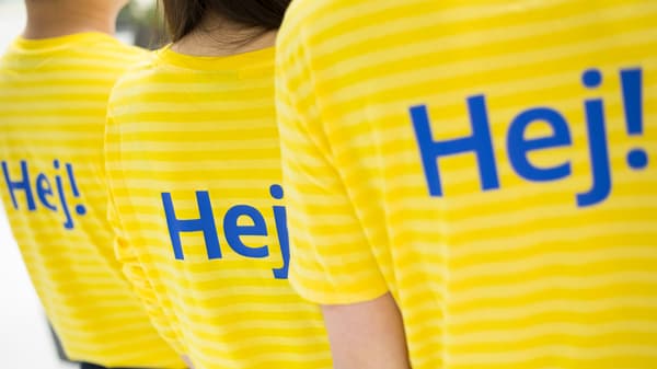 Hej！と書かれたイケアの制服を着た人が3人、背中を向けている