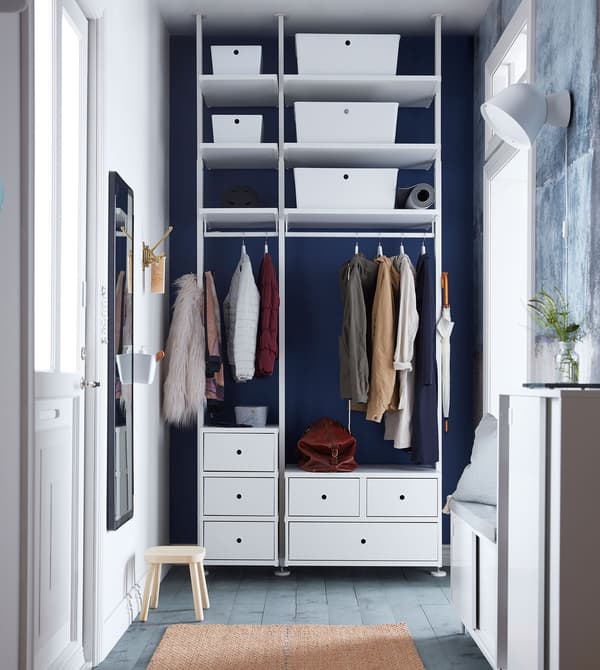 High gloss white KUGGIS storage boxes placed in a white storage system in a hallway setting.