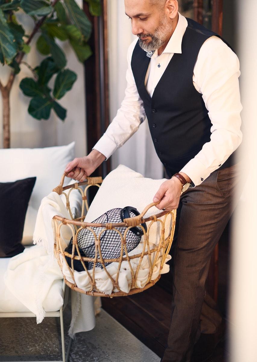 Hombre sosteniendo una canasta organizadora de color café con accesorios en su interior.