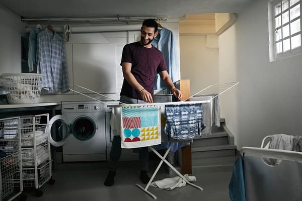 Homme accrochant des vêtements sur un séchoir.
