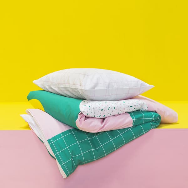 Housse de couette verte et rose déposée sur une tablette jaune et rose.