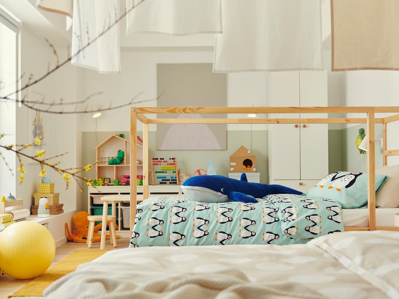 Houten KURA bed staat midden in een grote kinderkamer. Op het dekbed ligt een enorme walvisknuffel.