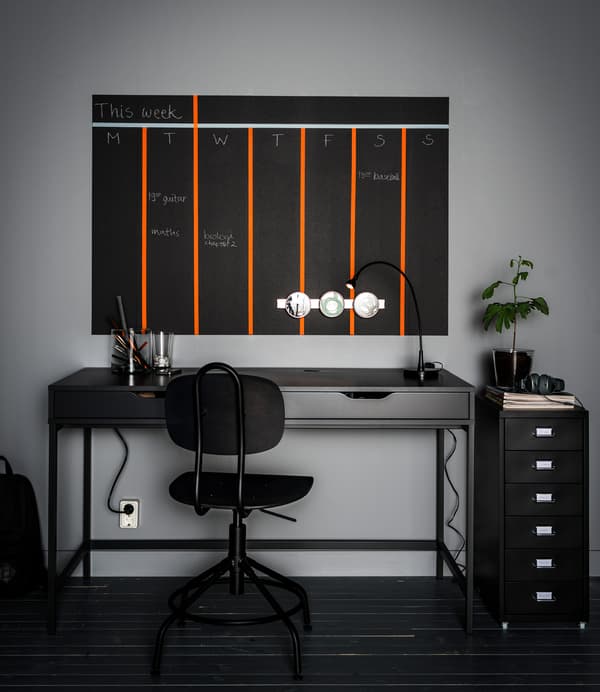 Idées rangement bureau: contenants aimantés et calendrier peint au mur, le tout installé au-dessus d’un bureau gris à deux tiroirs. Sans oublier l’accessoire pour tiroir qui permet de mettre de l’ordre dans les fournitures.