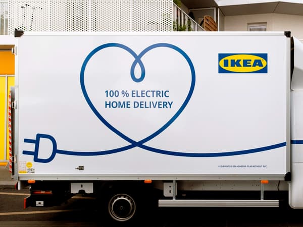 한 아파트 건물 옆에 주차되어 있는 흰색의 IKEA 100% 전기구동 가정배송 트럭.