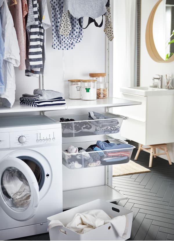 IKEA ALGOT laundry storage, combining clothing rails, mesh netted baskets and white shelves, near a washing machine.