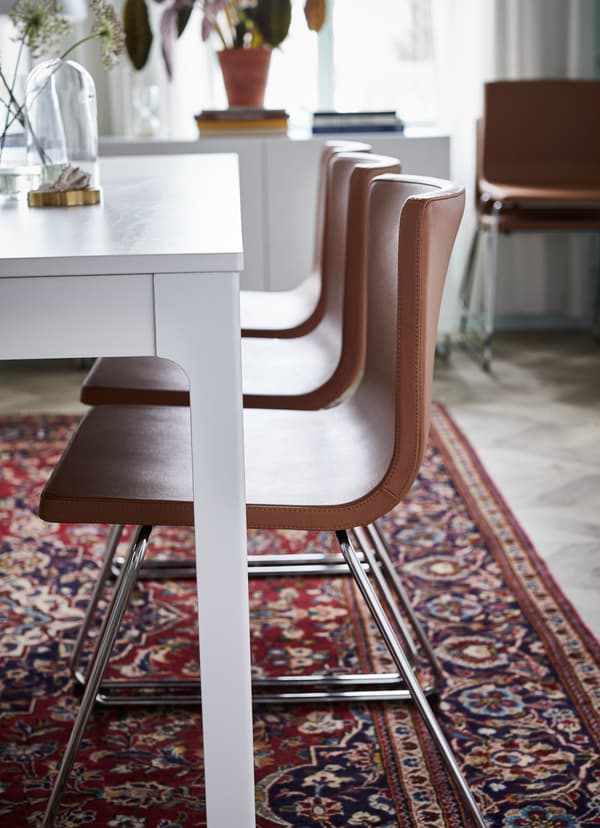 IKEA BERNHARD golden brown leather seats arranged in a line down a white dining table.