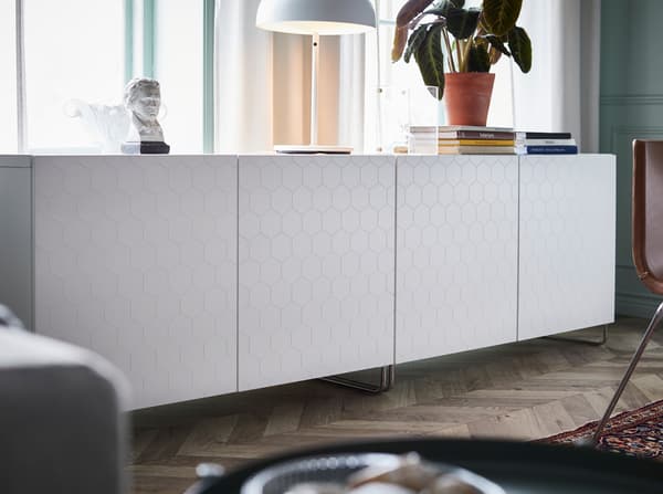 IKEA BESTÅ closed storage cabinet system with glossy white honeycomb VASSVIKEN doors and SULARP curved chrome legs.