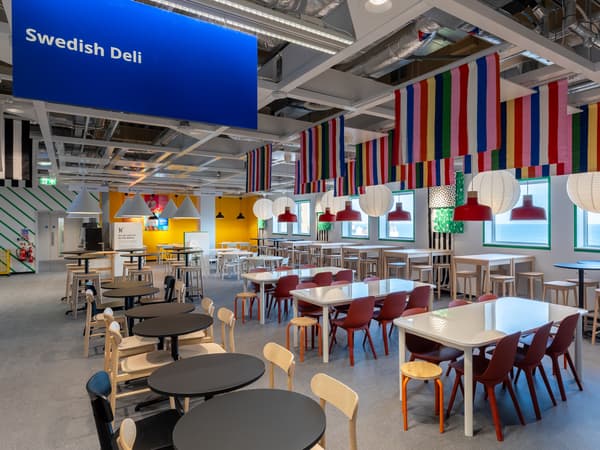 IKEA Brighton Swedish Deli, with white tables and red dining chairs, colourful banners hanging from the ceiling.