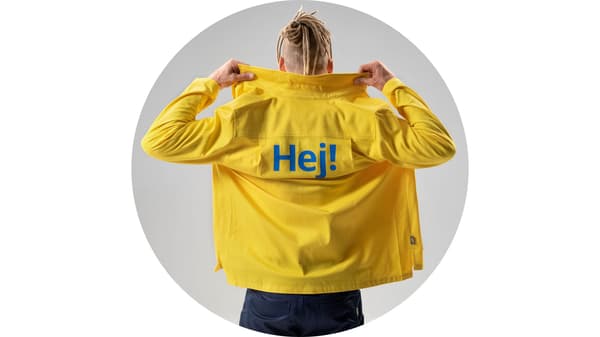 IKEA co-worker in a yellow jacket with the Swedish word 'Hej!