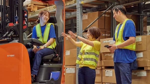 IKEA co-worker in a yellow shirt sealing a package with a hot glue gun.