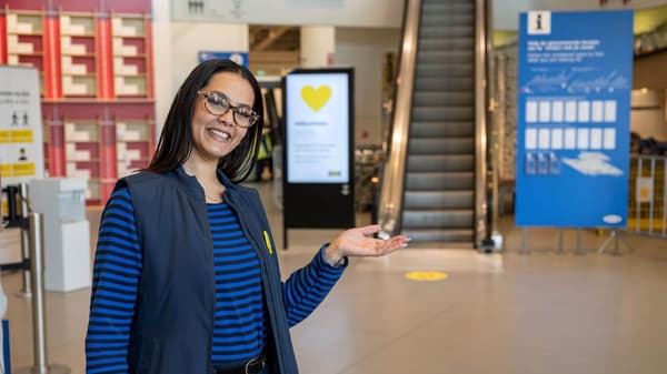 IKEA coworker welcoming you into IKEA towards an escalator