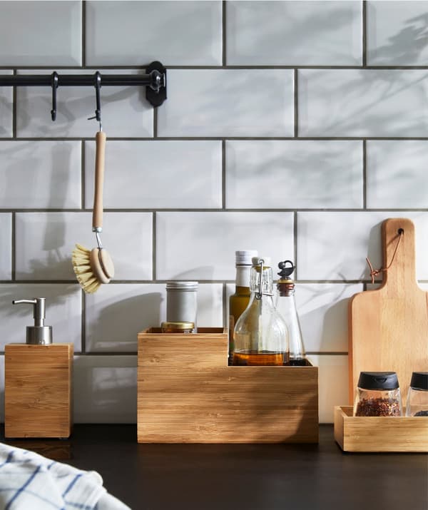 IKEA DRAGAN box in bamboo filled with kitchen countertop items on a kitchen worktop.