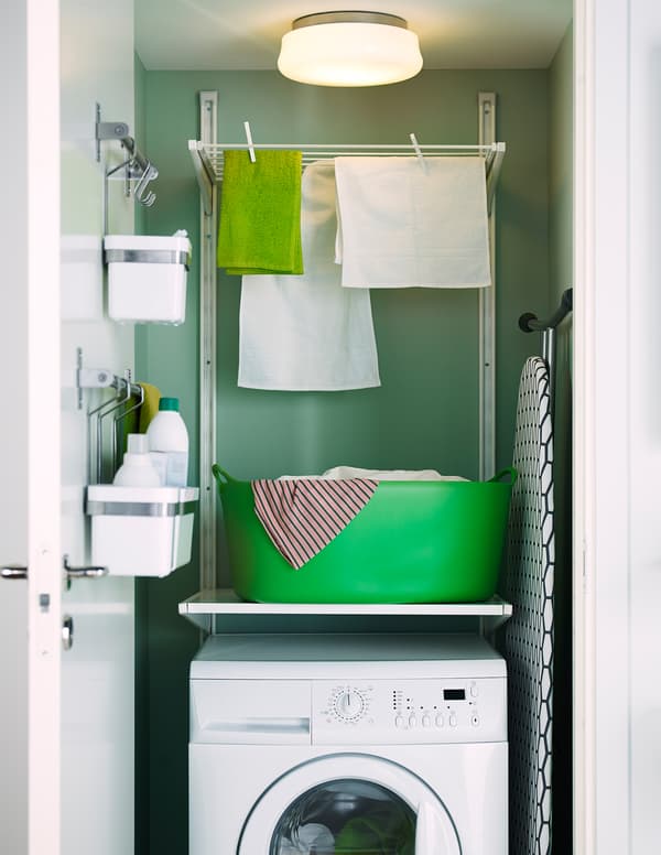 IKEA drying rack fixed to the wall above a washing machine in a closet laundry.