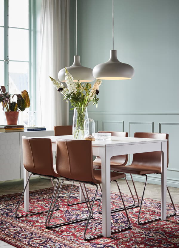 IKEA EKEDALEN white dining table with four brown leather BERNHARD seats.