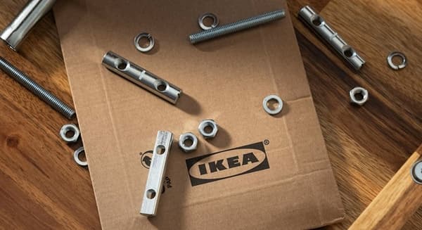 IKEA flatpack with scattered metal fasteners on a wooden surface.