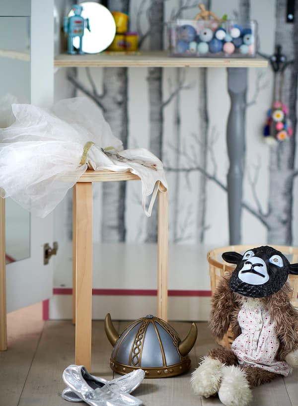 IKEA FROSTA stackable stool in birch plywood doubling as a small table to place costumes and stuffed toys when in use.