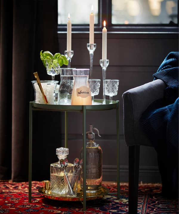 IKEA GLADOM tray table in green is decorated with glasses and tall white candles.