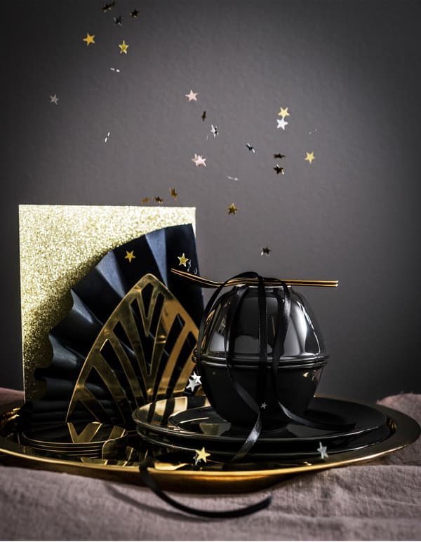 IKEA GLATTIS gold dinnerware and black VARDAGEN tableware make mealtime worth celebrating. Include shiny paper or a paper napkin fan for decor.