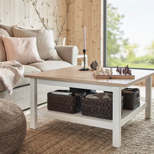 IKEA HEMNES coffee table with dark brown woven baskets underneath on its white shelf below.