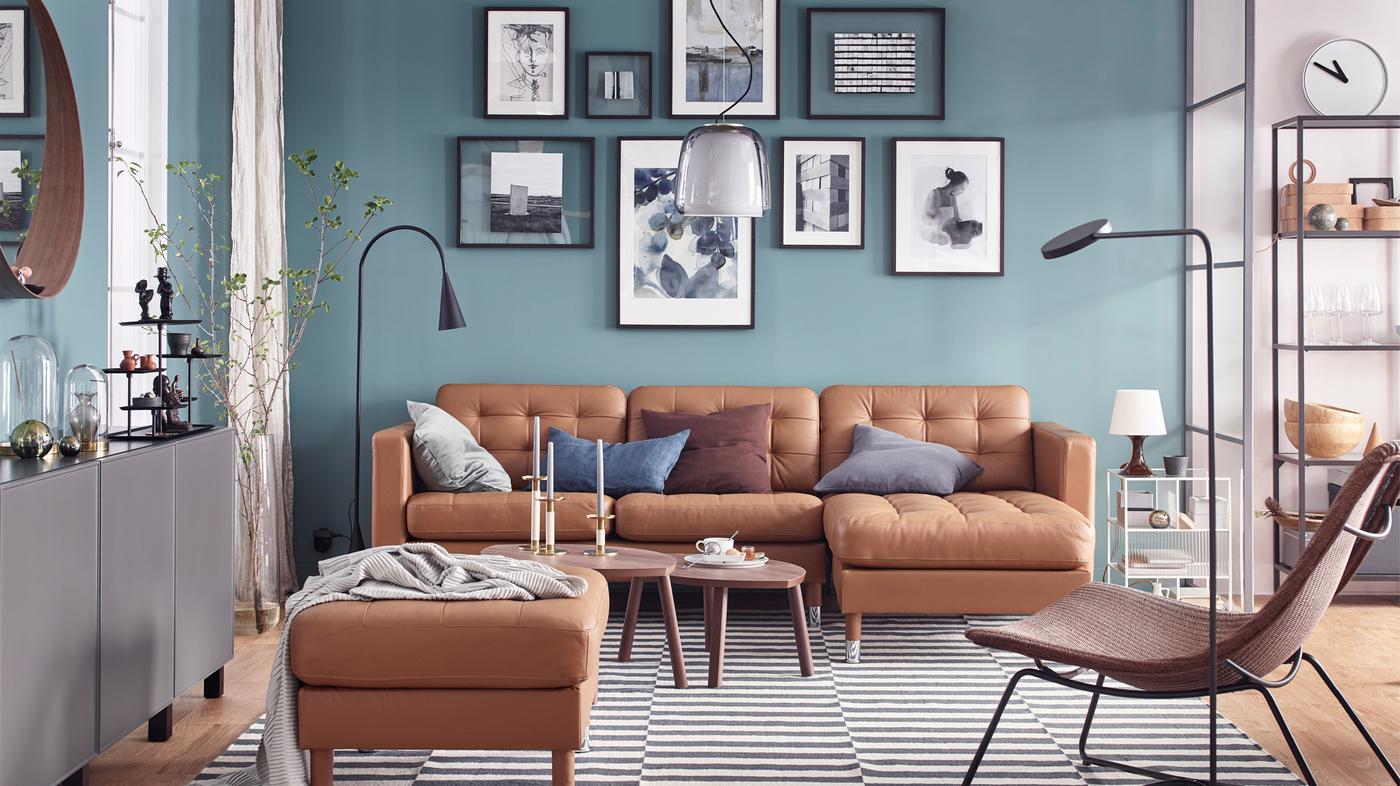 IKEA LANDSKRONA golden brown leather sofa with long chaise and footstool, against a teal wall in a living room space.