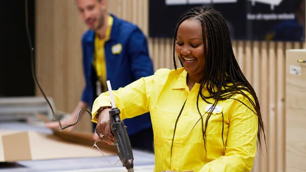 IKEA-medarbetare i gul skjorta förseglar ett paket med en limpistol.