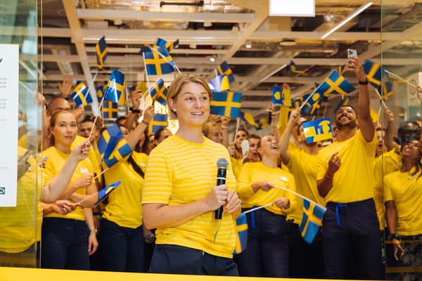 IKEA-medarbetare i gula tröjor viftar med svenska flaggor.
