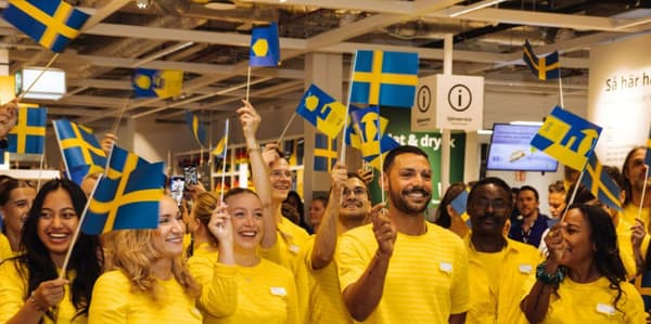 IKEA Medarbetare i varuhuset som skrattar och viftar på den svenska flaggan, utklädda i sina gula IKEA tröjor.