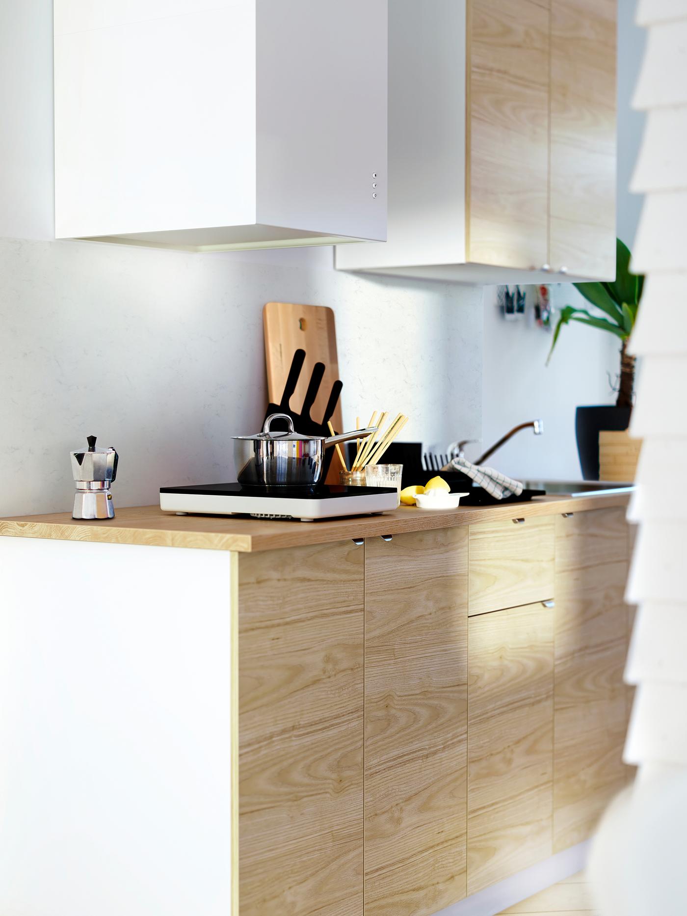 ארונות IKEA METOD עם חזיתות ASKERSUND חלקות בגוון מילה ומשטח עבודה מעץ שעליו כירה ניידת.