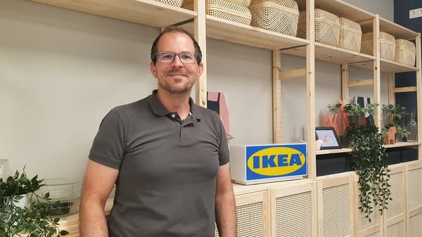 IKEA Mitarbeiter, der vor einem Regalhintergrund steht.