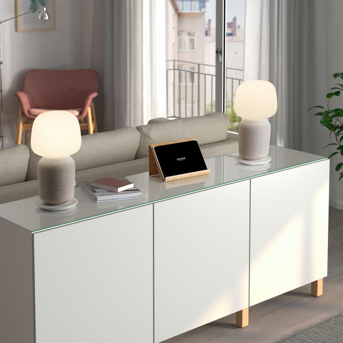 IKEA modern white sideboard behind a beige sofa in a living room with two SYMFONISK lamps on it