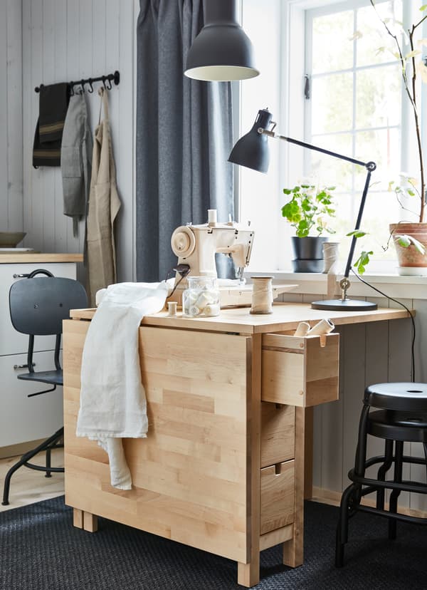 IKEA NORDEN extendable pine gateleg table with one half of the table surface propped down.