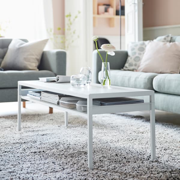 IKEA NYBODA long white coffee table with books stored underneath on a thin, slim shelf.