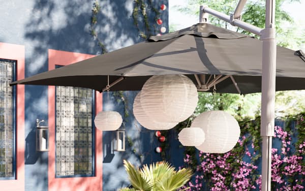 IKEA OXNÖ tiltable parasol frame and LINDÖJA black polyester canopy covering a collection of SOLVINDEN white paper lantern pendant lamps.