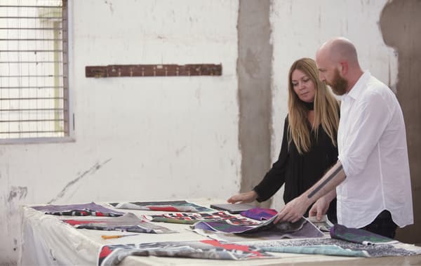 IKEA Range Manager Karin Gustavsson and Designer Martin Bergström looking at colourful fabrics on a large table.
