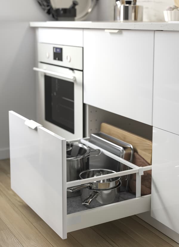 IKEA RINGHULT white glossy kitchen drawers, with one drawer open to show pots and pans store underneath the sink.