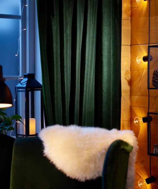 IKEA SANELA dark green cotton curtains behind a chair with a sheepskin.