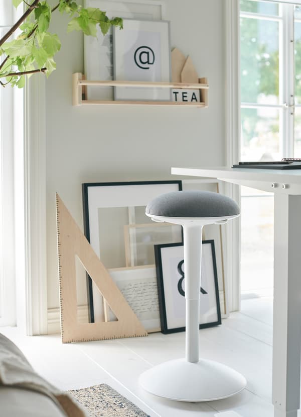 IKEA SKARSTA white sit and stand desk has a crank to adjust the worktop’s height. NILSERIK stool with light grey cushion also adjusts for flexible seating.