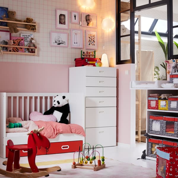 IKEA STUVA white baby furniture crib and six drawer unit in a pink children's nursery room with toys and stuffed panda bear.