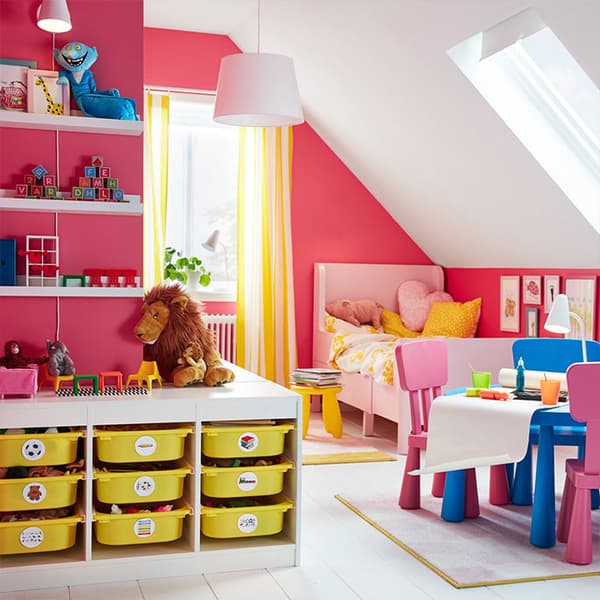 IKEA TROFAST white storage combination unit with nine yellow plastic bin shelves in a bright pink children's room.