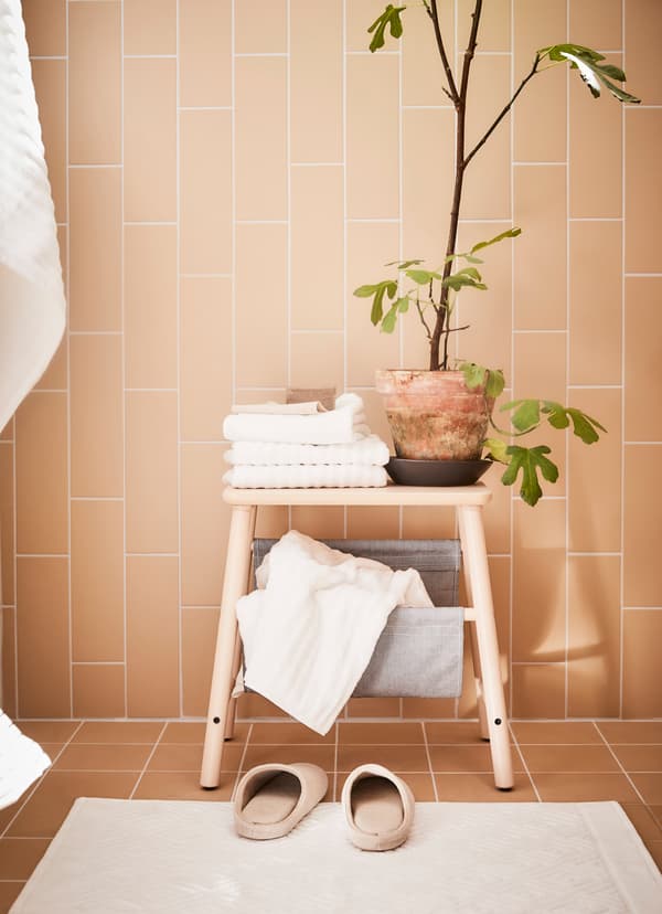 IKEA VILTO step stool with a potted plant and white hand towels on top.