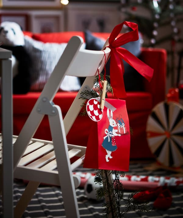 IKEA VINTER gift bag and tags hanging on the back of a white chair.
