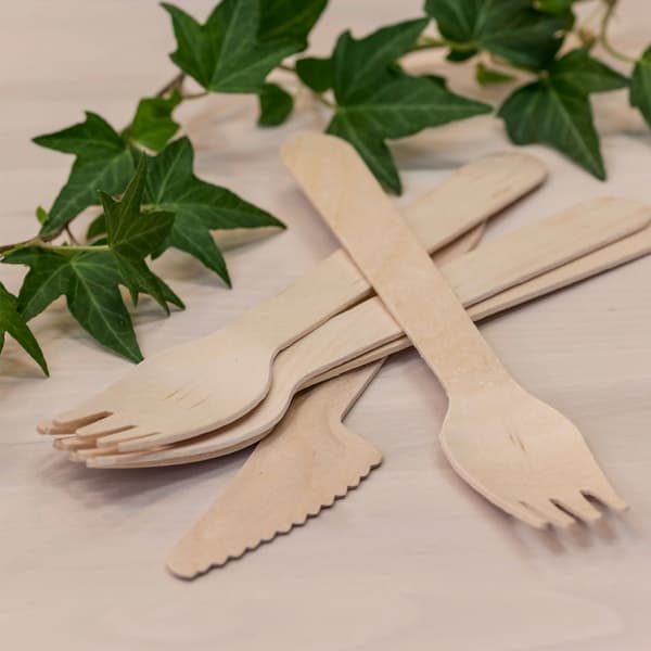 IKEA wooden fork and knife disposables lying on a wooden bench.