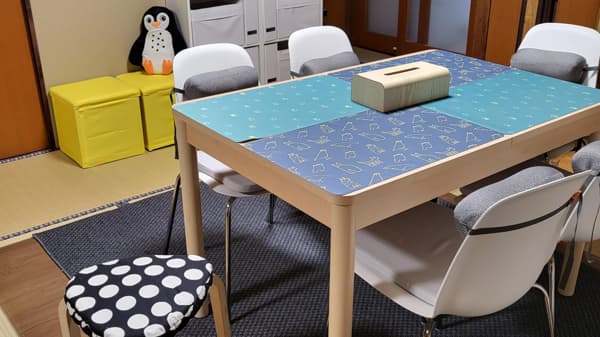 青いクロスが敷かれたテーブルに椅子が並んでいる。