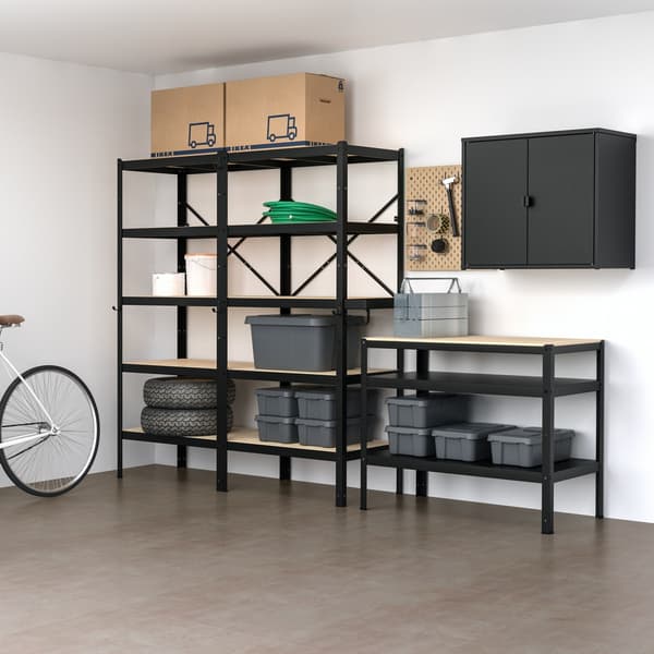 Imagen renderizada de un mueble BROR en un espacio cubierto con piso de hormigón pulido y muros blancos. El mueble, de metal negro, se compone de repisas, un gabinete cerrado y un módulo con mesa intependiente. 