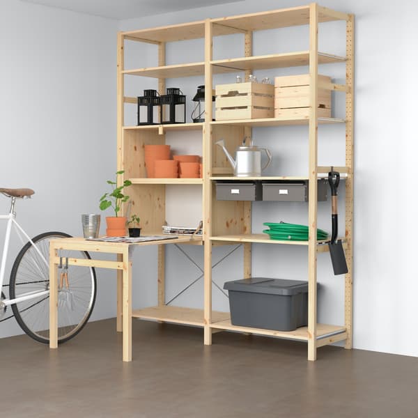 Imagen renderizada de un mueble BROR en un espacio cubierto con piso de hormigón pulido y muros blancos. El mueble, de madera de pino, se compone de repisas y un módulo de mesa plegable. 