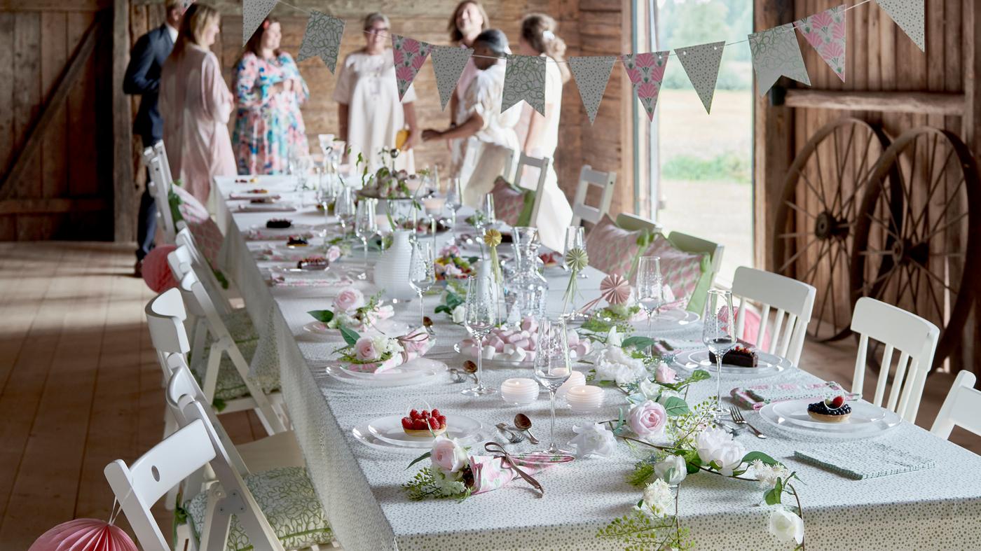 In a barn, a table is set up for a party with glassware, tableware and decoration from the INBJUDEN festive collection.