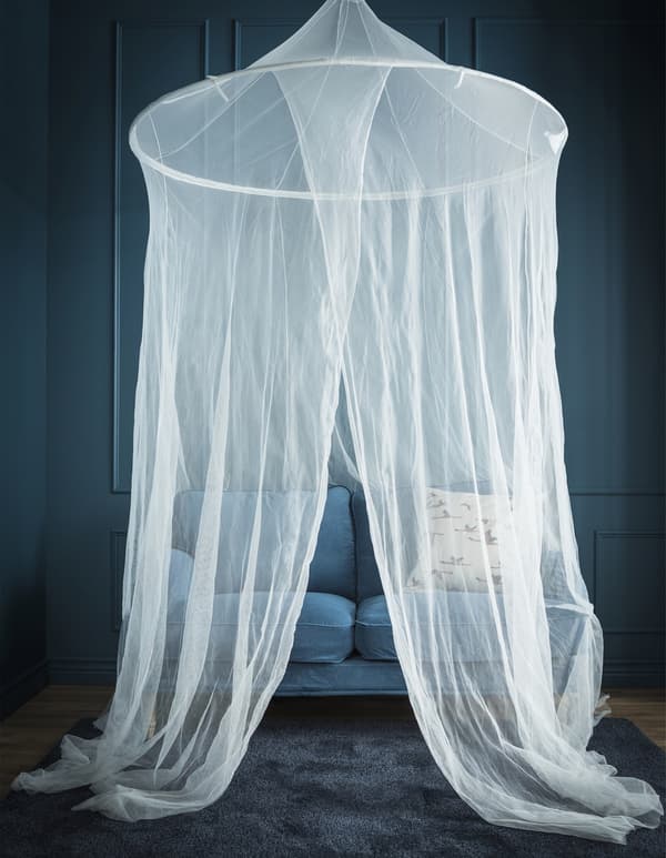 In a blue room, a canopy net is hung above a small blue sofa.