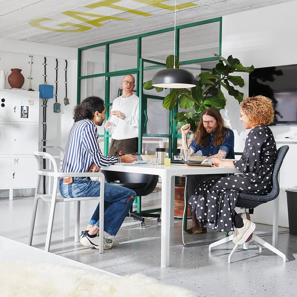 In a conference room, employees sit at a table during a meeting