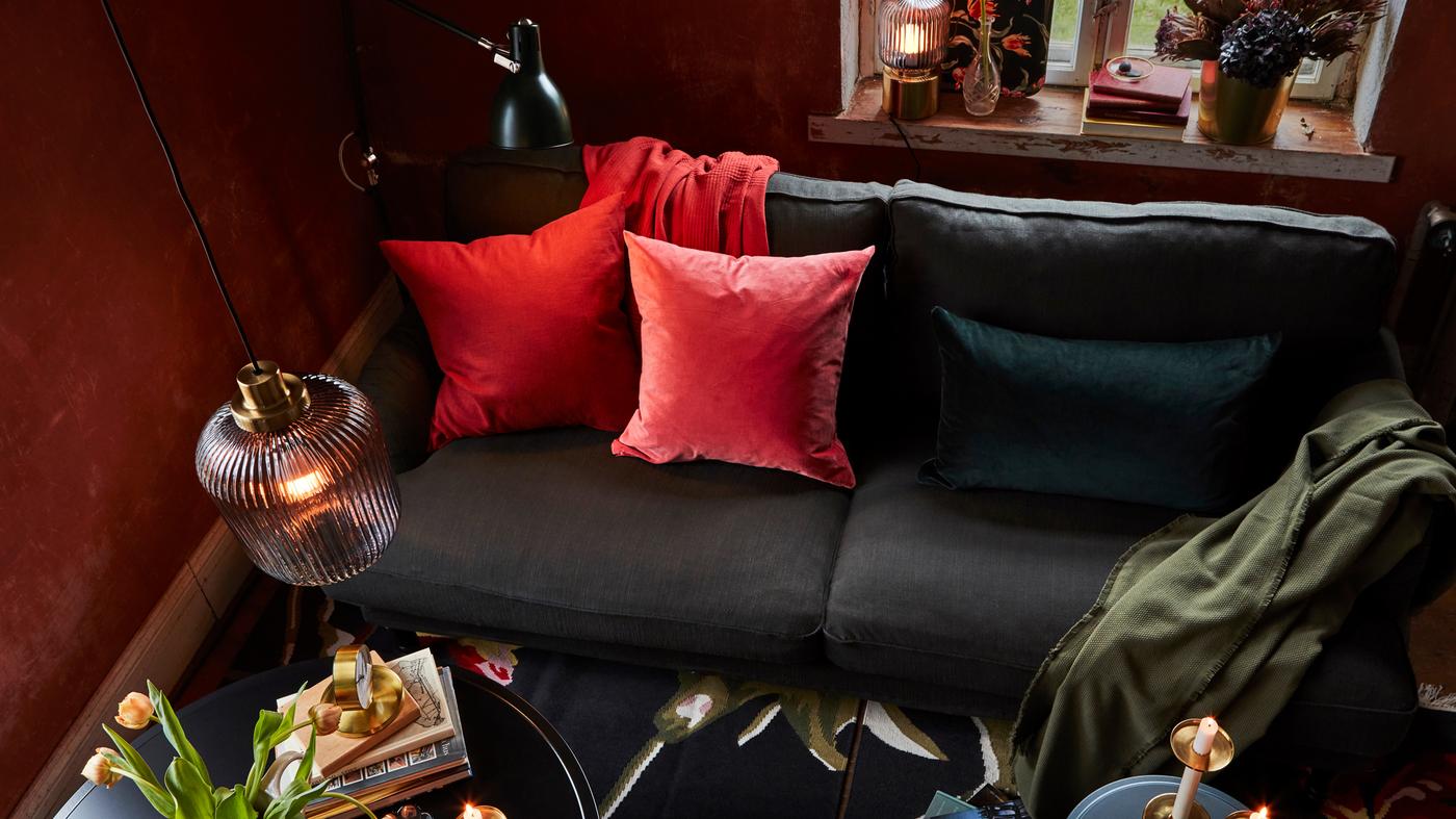 In a living room, a mix of pendant, floor and table lamps and a sofa with colourful cushions help set a warm, cozy mood.