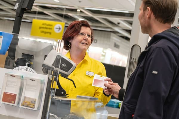 In an IKEA store, a customer is buying an IKEA Gift Card from a cashier.